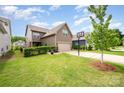 A rear view of the home shows a lawn, patio and a basketball hoop on a paved drive at 915 Claires Creek Ln, Davidson, NC 28036