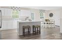 Eat-in kitchen with white cabinetry, quartz countertops, an island with barstools, and hardwood floors at 10108 Florentine Way, Charlotte, NC 28214