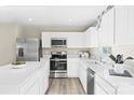 Bright kitchen with stainless steel appliances, white cabinets, quartz countertops, tile backsplash, and plank flooring at 10108 Florentine Way, Charlotte, NC 28214