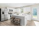Modern kitchen features white cabinetry, stainless steel appliances, quartz countertops, and a kitchen island with barstool seating at 10108 Florentine Way, Charlotte, NC 28214