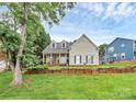 Charming two-story home featuring a stone porch, dormer windows, green shutters, and a beautifully landscaped front yard at 10449 Quiet Bay Ct, Charlotte, NC 28278