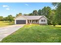 Inviting single-story home with an attached garage, front porch, and green lawn at 105 Saddlewood Ln, Statesville, NC 28625