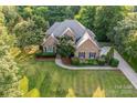 Brick home featuring a large manicured lot, mature trees and landscaping, and a private driveway at 1115 Maremont Ct, Matthews, NC 28104