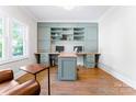 Bright office space featuring custom-built-in shelving, cabinets, hardwood floors, and a comfortable seating area at 1280 Winged Foot Dr, Denver, NC 28037