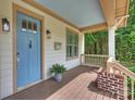 Charming front porch featuring a blue door, wooden floors, brick accents, and a cozy spot for potted plants at 1315 Charles Ave, Charlotte, NC 28205