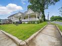 Exterior view of a well-kept lawn with a charming house and inviting front porch along a sidewalk at 211 S Rowan Ave, Spencer, NC 28159