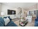 Cozy living room with plush seating, a large TV, decorative rug and staircase to the upper level at 3722 Ellington St, Charlotte, NC 28211