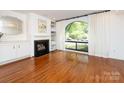Elegant living room featuring hardwood floors, a fireplace, built-in shelving, and a large arched window at 5809 Sharon Rd # G, Charlotte, NC 28210
