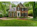 Charming brick and siding home with manicured lawn, mature trees and black shutters at 8624 Canter Post Dr, Charlotte, NC 28216