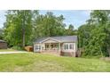 Tan single story home featuring a welcoming front porch, gray shutters, green grass, and a gravel driveway at 119 Wade Dr, Kings Mountain, NC 28086