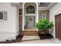 Elegant entryway with stone accents, a decorative wreath, and stylish outdoor lighting at 20312 Deep Cove Ct, Cornelius, NC 28031