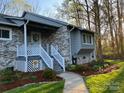 Close-up of gray brick home with a welcoming porch, stylish railings, and lush landscaping in the front yard at 205 Wellington Hills Cir # 205, Salisbury, NC 28147
