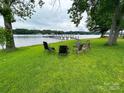 Lawn chairs and a grill sit on a grassy lawn, with a dock and lake in the background, ideal for enjoying outdoor living at 4574 Ivy Run Ln, Denver, NC 28037