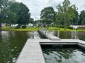 View from the dock to the home with a well manicured lawn, trees, and serene lake, creating a peaceful waterfront retreat at 4574 Ivy Run Ln, Denver, NC 28037
