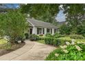 Inviting white brick home featuring mature trees, lush landscaping, and a curved walkway at 829 Sedgefield Rd, Charlotte, NC 28209