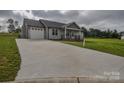 View of a wide concrete driveway leading to a light gray one-story house with an attached garage at 108 Devynne Ct, Salisbury, NC 28146