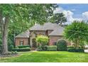 Charming brick home with lush lawn, mature trees, manicured landscaping, and classic architectural details at 14652 Villalonga Ln, Charlotte, NC 28277