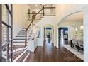 Grand foyer featuring hardwood floors, a staircase with white balusters, and arched entryways into the living spaces at 14652 Villalonga Ln, Charlotte, NC 28277