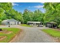 Wide exterior shot showcases the gravel driveway, home, and two outbuildings at 2289 Mccloud St, Denver, NC 28037
