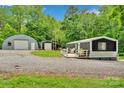 Wide exterior shot showcases the gravel driveway, home, and two outbuildings at 2289 Mccloud St, Denver, NC 28037
