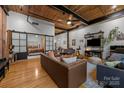 Open-concept living room with exposed wood ceiling, hardwood floors, and sliding door to the bedroom at 310 Arlington Ave # 409, Charlotte, NC 28203
