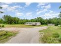 Wide shot of a tan single-story home with a gravel driveway and surrounding greenery and a shed at 4518 Logging Rd, Lancaster, SC 29720