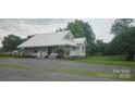 The home features a beautiful lawn, mature trees, covered porch, and convenient gravel driveway at 804 N Main St, Oakboro, NC 28129