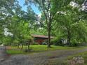 A single-story home with a lush green front yard surrounded by beautiful trees at 823 Corbin St, Albemarle, NC 28001