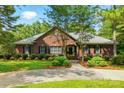 Beautiful red brick home with a well-kept lawn, mature trees, and a spacious driveway leading to a welcoming entrance at 102 Rosewood Ln, Locust, NC 28097