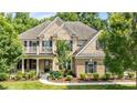 Beautiful brick home featuring a front porch, second-story balcony, and well-manicured lawn at 10508 Kristens Mare Dr, Charlotte, NC 28277