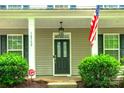 Charming home showcasing a covered front porch, complemented by well-maintained landscaping and an American flag at 10732 Trolley Run Dr, Cornelius, NC 28031