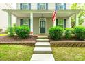 Charming home showcasing a covered front porch, complemented by well-maintained landscaping and an American flag at 10732 Trolley Run Dr, Cornelius, NC 28031