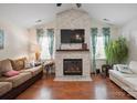 Bright living room features vaulted ceilings, brick fireplace, ceiling fan, wood flooring and comfortable seating at 119 Ashwood Ln, Mooresville, NC 28117