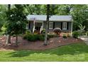 Charming single-story home with a landscaped front yard and classic architectural details including gray siding and black shutters at 1230 Somersby Ln, Matthews, NC 28105