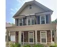 Two-story home showcasing a stone facade, second-story balcony, covered porch, and manicured greenery at 12904 Windy Lea Ln, Huntersville, NC 28078