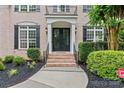Inviting front entrance with a black front door, brick steps, and lush greenery at 13716 Glen Abbey Dr, Charlotte, NC 28278