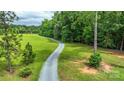 Gravel driveway leading through a lush green lawn and mature trees at 15025 Barbee Rd, Stanfield, NC 28163