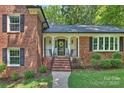 Inviting front porch featuring brick steps, decorative columns and railings, and a lovely wreath on the front door at 2301 Seth Thomas Rd, Charlotte, NC 28210