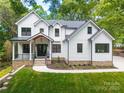 Charming two-story modern farmhouse features a stone foundation and manicured lawn at 3601 Woody Grove Ln, Charlotte, NC 28210