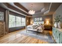 A spacious primary bedroom with tray ceilings, hardwood floors, a large window and a sitting area at 4712 Amberside Dr, Rock Hill, SC 29732