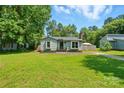 Inviting single-story home on a green lawn under a sunny sky with mature trees at 6718 Pueblo Ln, Charlotte, NC 28227