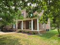 Classic brick home boasts a charming covered porch with white columns at 8409 Olde Stonegate Ln, Mint Hill, NC 28227