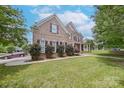 Elegant brick home featuring well-manicured lawn and mature landscaping with shade trees at 8409 Olde Stonegate Ln, Mint Hill, NC 28227
