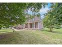 Stately brick home with columned front porch, trimmed shrubs, and lush lawn at 8409 Olde Stonegate Ln, Mint Hill, NC 28227