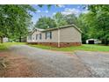 A gravel driveway leads to a cozy home with tidy landscaping and a storage shed at 1245 Forest Ridge Rd, Bessemer City, NC 28016
