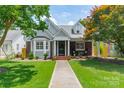Beautiful brick and gray home with lush green lawn and inviting front porch seating area at 2021 Charlotte Dr, Charlotte, NC 28203
