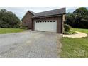 Attached garage featuring a white door and gravel driveway at 28835 Hartsell Rd, Albemarle, NC 28001