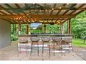 Outdoor bar with a wooden counter, barstools, a mounted TV, and string lights at 625 S Magnolia St, Mooresville, NC 28115