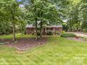 Charming brick home featuring a welcoming front porch, lush landscaping, and mature trees at 635 Timberlane Trl, Salisbury, NC 28147