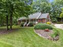 Charming brick home featuring a welcoming front porch, lush landscaping, and mature trees at 635 Timberlane Trl, Salisbury, NC 28147